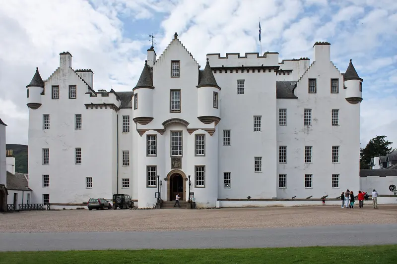 The white-harled towers and turrets of Blair Castle above a gravel forecourt and lawn
